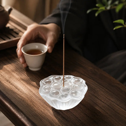 Hand holding a glass lotus incense holder with ash catcher for mindful incense use